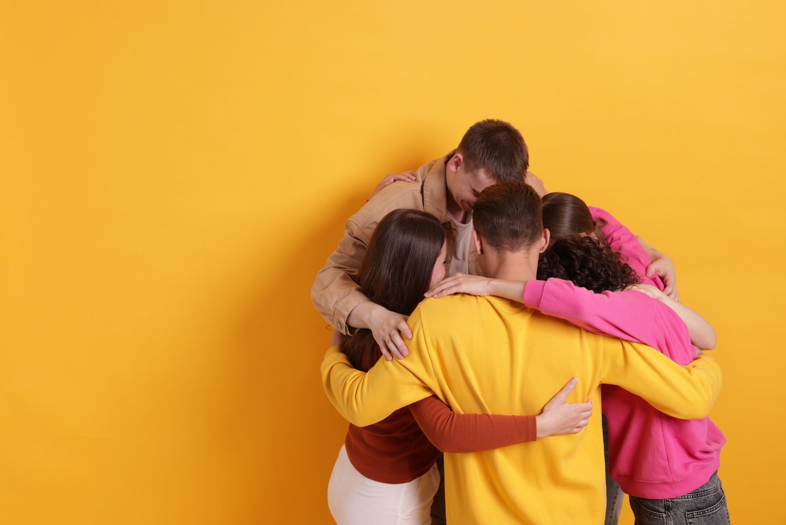 Group of friends hugging each other on orange background, space for text