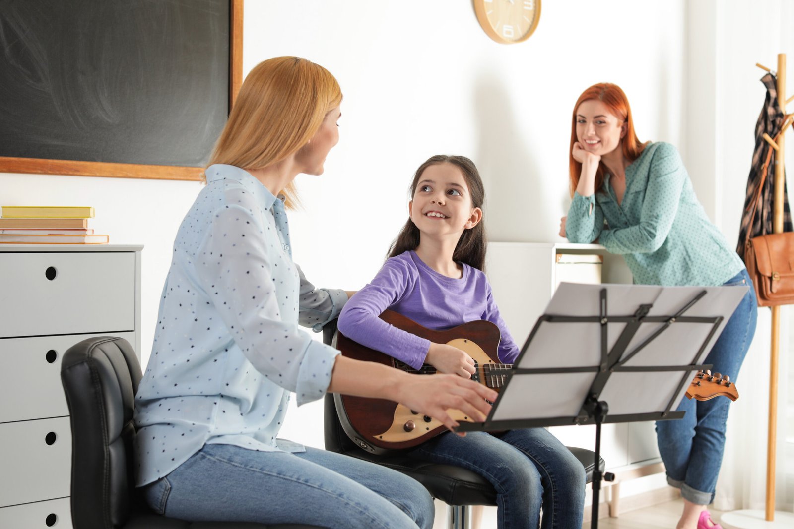 Little girl with her teacher and mother at music lesson. Learning notes Little girl with her teacher and mother at music lesson. Learning notes